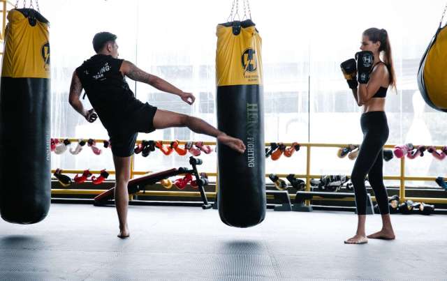 strong male personal trainer showing kickboxing technique to young woman